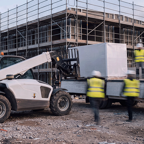 Lieferlogistik auf der Baustelle – Teleskoplader entlädt Baumaterial vor dem Gerüst