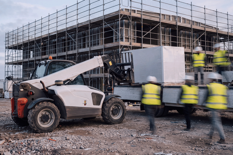 Teleskoplader entlädt verpacktes Baumaterial von einem LKW auf der Baustelle