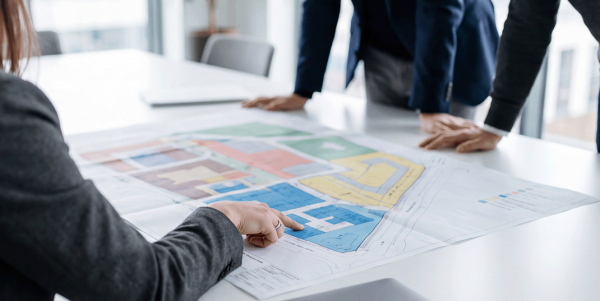 Projektbesprechung – Team plant Baulogistik anhand eines Lageplans im Büro